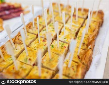 food, cooking and eating concept - close up of casserole or quiche pieces served with skewers