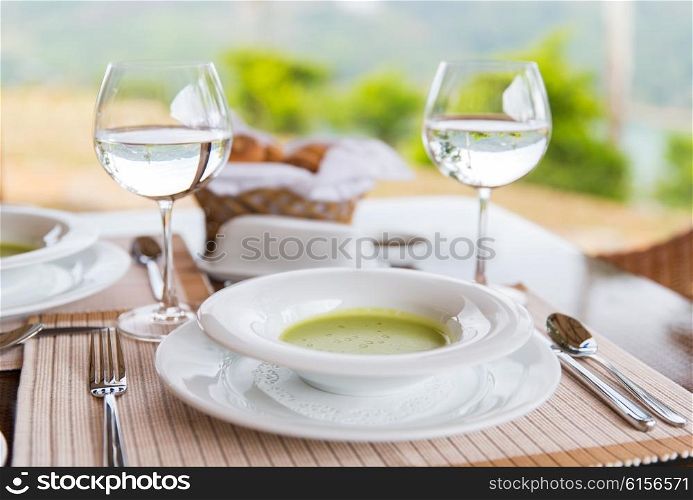 food, cooking and eating concept - close up of creamy soup and water glasses on table at restaurant or home