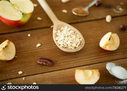 food cooking and eating concept - oatmeal in spoon, cut apples and nuts on wooden table. oatmeal in wooden spoon, cut apples and nuts