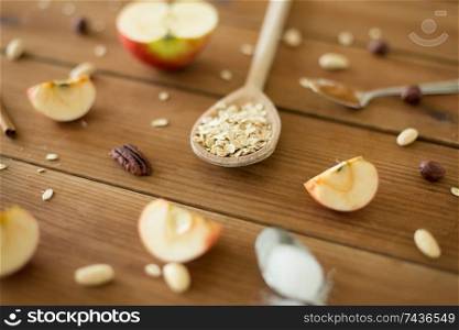 food cooking and eating concept - oatmeal in spoon, cut apples and nuts on wooden table. oatmeal in wooden spoon, cut apples and nuts