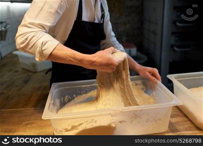 food cooking, baking and people concept - baker kneading dough and making bread at bakery kitchen. baker making bread dough at bakery kitchen