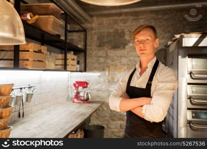food cooking, baking and people concept - chef or baker in apron at bakery kitchen. chef or baker in apron at bakery kitchen