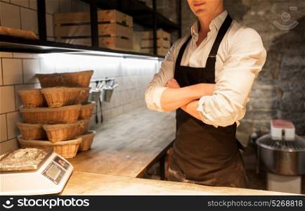 food cooking, baking and people concept - chef or baker in apron at bakery kitchen. chef or baker in apron at bakery kitchen