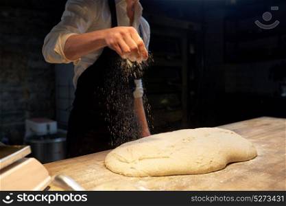 food cooking, baking and people concept - chef or baker making bread and pouring flour to dough at bakery. chef or baker making bread dough at bakery