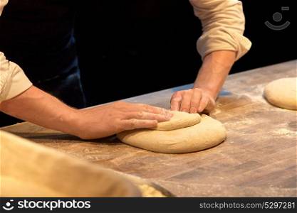 food cooking, baking and people concept - chef or baker making dough at bakery. chef or baker cooking dough at bakery