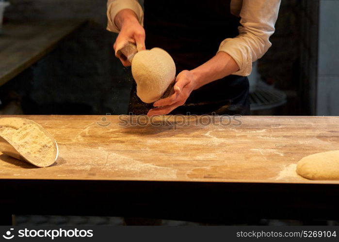 food cooking, baking and people concept - chef or baker portioning dough with bench cutter at bakery. baker portioning dough with bench cutter at bakery