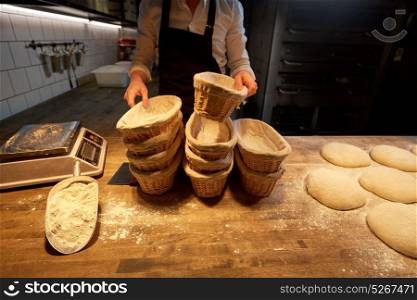 food cooking, baking and people concept - chef or baker preparing baskets while dough rising at bakery kitchen. baker with baskets for dough rising at bakery