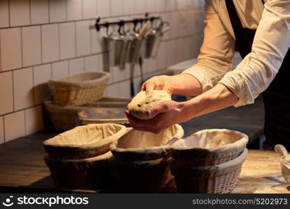 food cooking, baking and people concept - chef or baker putting yeast bread dough into baskets for rising at bakery kitchen. baker with dough rising in baskets at bakery