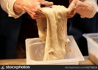 food cooking, baking and people concept - close up of baker hands kneading dough and making bread at bakery. close up of baker hands making bread dough