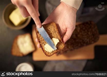 food cooking, baking and people concept - female baker spreading butter on slice of homemade bread. female baker spreading butter on homemade bread