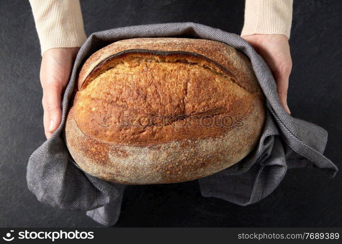 food cooking, baking and people concept - female baker with loaf of bread at bakery or kitchen. female baker with homemade bread at bakery