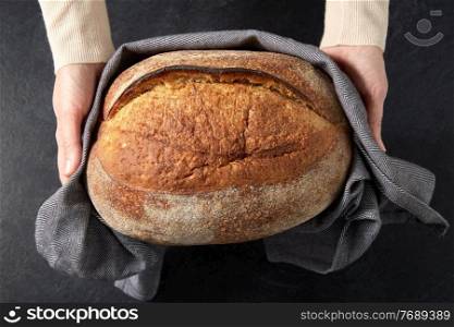 food cooking, baking and people concept - female baker with loaf of bread at bakery or kitchen. female baker with homemade bread at bakery