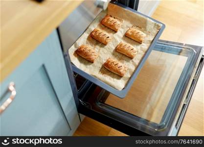 food cooking, culinary and pastry concept - baking tray with jam pies in oven at home kitchen. baking tray with jam pies in oven at home kitchen