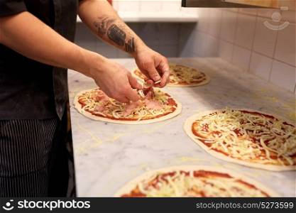 food cooking, culinary and people concept - cook or baker hands adding champignons to pizza at pizzeria. cook hands adding champignons to pizza at pizzeria