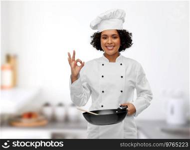 food cooking, culinary and people concept - happy smiling female chef with frying pan showing ok gesture over restaurant kitchen background. female chef with frying pan showing ok in kitchen