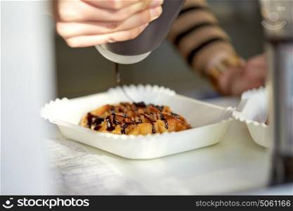 food, cooking, dessert and people concept - close up of cook adding chocolate syrup to waffle. close up of cook adding syrup to waffle