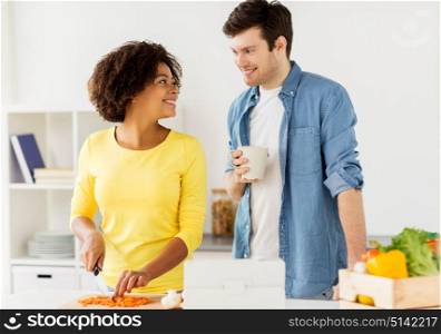 food, cooking, people, international and healthy eating concept - happy couple with tablet pc computer chopping vegetables and talking at home kitchen. happy couple cooking food at home kitchen