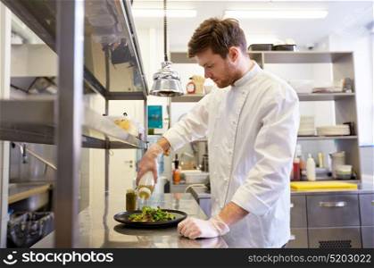 food cooking, profession and people concept - happy male chef cook making vegetable salad at restaurant kitchen. happy male chef cooking food at restaurant kitchen