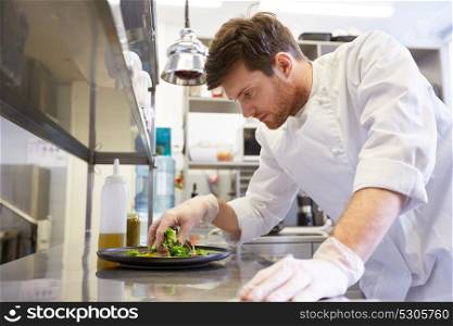 food cooking, profession and people concept - happy male chef cook making vegetable salad at restaurant kitchen. happy male chef cooking food at restaurant kitchen