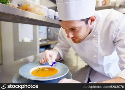food cooking, profession and people concept - happy male chef cook serving and decorating plate of soup with flower at restaurant kitchen. happy male chef cooking food at restaurant kitchen