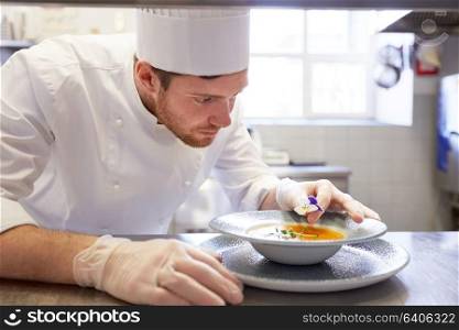 food cooking, profession and people concept - happy male chef cook serving and decorating plate of soup with flower at restaurant kitchen. happy male chef cooking food at restaurant kitchen