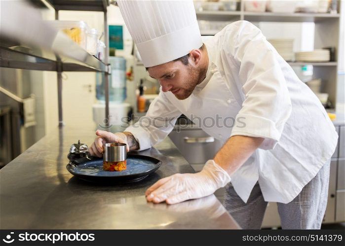 food cooking, profession and people concept - happy male chef cook with mold serving stewed vegetables on plate at restaurant kitchen. happy male chef cooking food at restaurant kitchen
