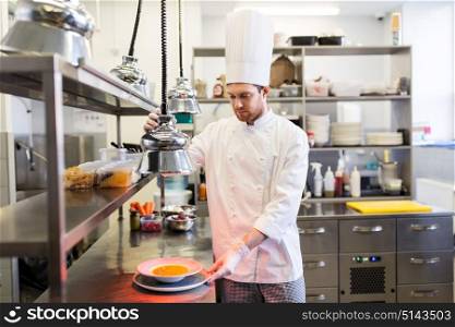 food cooking, profession and people concept - happy male chef cook with cloche serving plate of soup at restaurant kitchen. happy male chef cooking food at restaurant kitchen