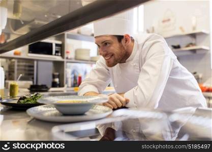 food cooking, profession and people concept - happy male chef cook with plate of soup and salad at restaurant kitchen table. happy male chef cooking food at restaurant kitchen