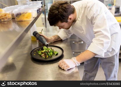 food cooking, profession and people concept - male chef cook serving plate of salad and seasoning it with balsamic vinegar sauce at restaurant kitchen. male chef cooking food at restaurant kitchen