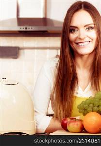 Food cuisine diet fruit natural concept. Smiling lady in kitchen. Female cook leaning on counter next to pile of fruits and kitchenware utensils.. Smiling lady in kitchen.