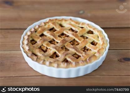 food, culinary and baking concept - apple pie on wooden table. apple pie in baking mold on wooden table