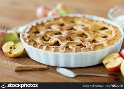 food, culinary and baking concept - close up of apple pie with cinnamon and sugar on wooden table. close up of apple pie on wooden table