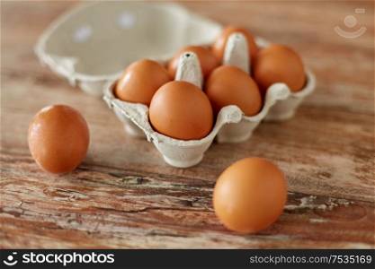 food, culinary and cooking concept - close up of natural chicken eggs in cardboard box on wooden table. close up of eggs in cardboard box on wooden table