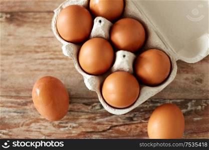 food, culinary and cooking concept - close up of natural chicken eggs in cardboard box on wooden table. close up of eggs in cardboard box on wooden table