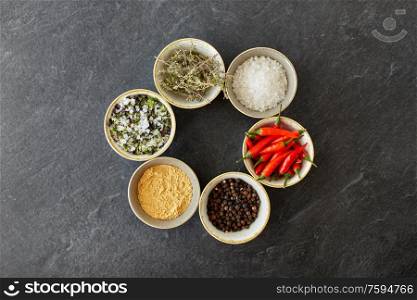 food, culinary and eating concept - bowls with different spices on slate stone table. bowls with different spices on slate stone table