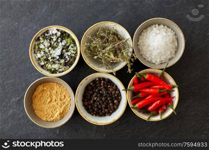 food, culinary and eating concept - bowls with different spices on slate stone table. bowls with different spices on slate stone table