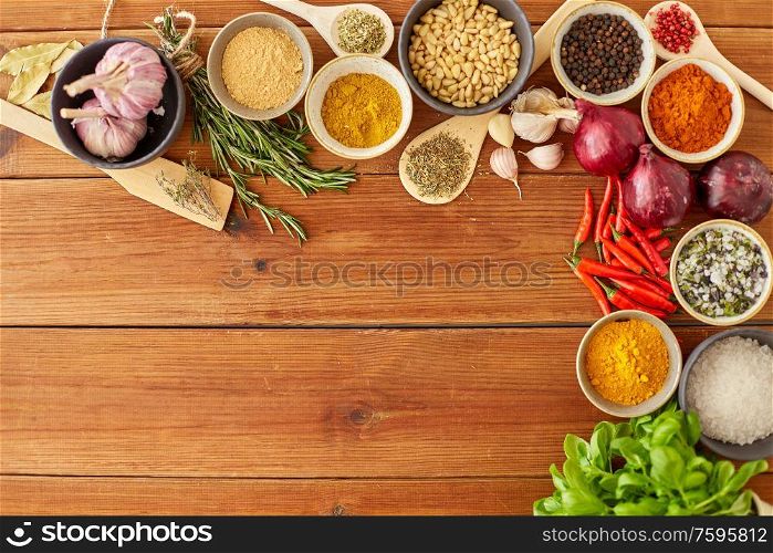 food, culinary and eating concept - bowls with different spices, onion, garlic with pine nuts and red hot chili pepper on wooden table. spices, onion, garlic, pine nuts and chili peppers