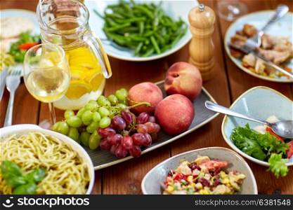 food, culinary and eating concept - fruits, salads, jug of orange water and pasta on wooden table. fruits, salads and pasta on wooden table
