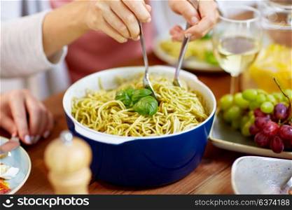 food, culinary and eating concept - hands taking pasta with basil from bowl on table. pasta with basil in bowl and other food on table