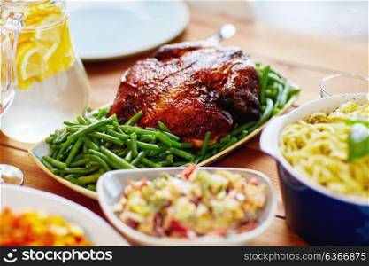 food, culinary and eating concept - roast chicken with garnish of green beans on served table. roast chicken with garnish of green beans on table