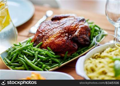food, culinary and eating concept - roast chicken with garnish of green peas on table. roast chicken with garnish of green peas on table