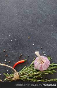 food, culinary and eating concept - rosemary, garlic, thyme and red chili pepper on stone surface. rosemary, garlic and chili pepper on stone surface