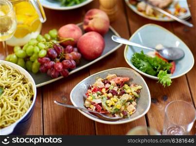 food, culinary and eating concept - smoked chicken salad, fruits and pasta on wooden table. salad, fruits and pasta on wooden table