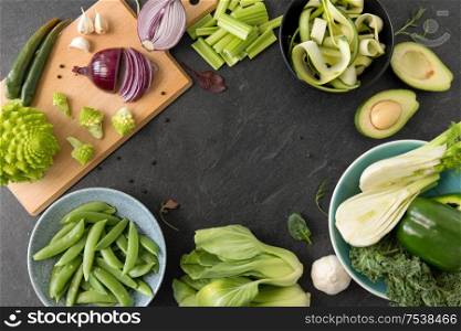 food, culinary and healthy eating concept - close up of different green vegetables and fruits on slate stone background. close up of different green vegetables