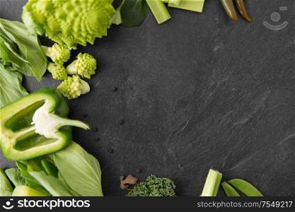 food, culinary and healthy eating concept - close up of different green vegetables on slate stone background. close up of different green vegetables