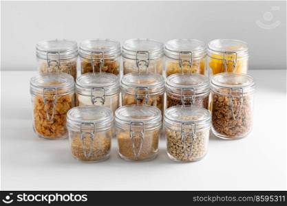 food, culinary and storage concept - jars with different cereals, pasta, beans and cookies on white background. jars with cereals, pasta, beans and cookies