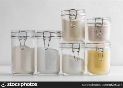 food, culinary and storage concept - jars with different kinds of flour sugar and salt on white background. close up of jars with flours, sugar and salt