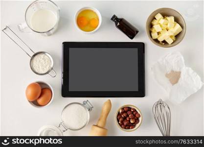 food, culinary and technology concept - tablet pc computer and cooking ingredients on table. tablet computer and cooking ingredients on table