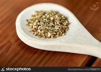 food, culinary and unhealthy eating concept - close up of dry spices on wooden spoon. close up of dry spices on wooden spoon