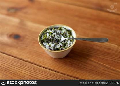 food, culinary and unhealthy eating concept - close up of flavored sea salt in bowl with spoon on wooden table. close up of flavored sea salt in bowl with spoon